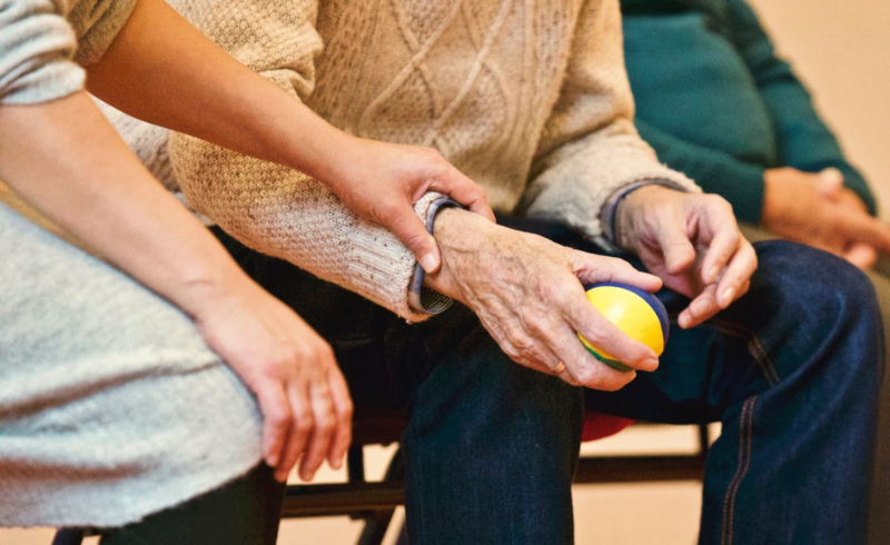 braccio di uomo seduto sostenuto dalla mano di un aiutante 